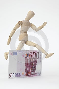 Jointed doll jumping over a 500-Euro-Banknote photo