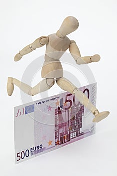 Jointed doll jumping over a 500-Euro-Banknote photo