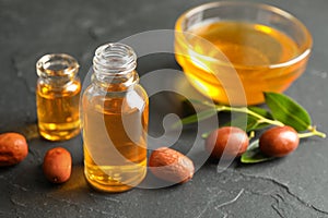 Jojoba oil and seeds on grey table