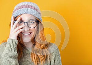 Joke. Happy woman looking through his fingers, isolated on yellow background. Playful trendy girl