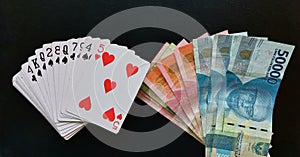 Joker combination of joker card with rupiah\'s banknotes money on black background