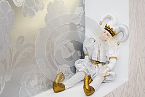 Joker doll, on white background. Doll harlequin, decoration of the hall,