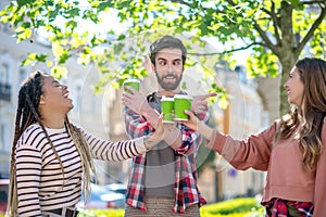 Joking cross-eyed guy and two laughing girls standing on street