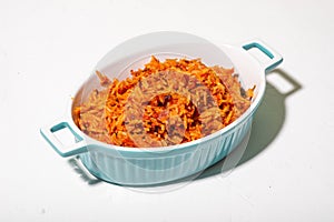 Jollof rice in a dish on a white background. Traditional Nigerian food made from rice, tomatoes and spices