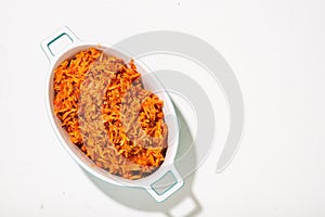 Jollof rice in a dish on a white background. Traditional Nigerian food made from rice, tomatoes and spices. Top view, place for