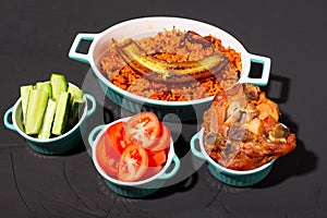 Jollof rice with fried banana, baked chicken. Rice with tomatoes, onions, spices. Traditional national Nigerian food. Dark