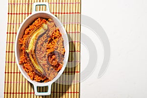 Jollof rice with fried banana. Traditional Nigerian rice food with tomatoes, onions and spices. Light background. View from above