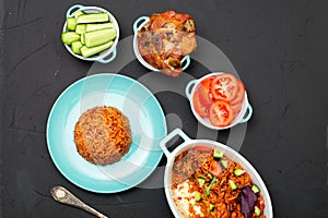 Jollof rice on a plate. Rice with tomatoes, onions, spices. Traditional national Nigerian food. Dark background