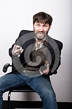 Jolly bearded man in a jacket and jeans, sitting on a chair and holding a gun. gangster concept