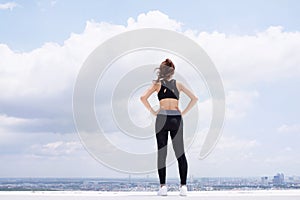 Jolly girl in sportswear is standing on terrace and looking forward