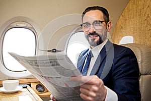 Jolly imposing man relaxing with newspaper