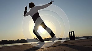 Jolly man dances actively on a river bank in summer in slo-mo