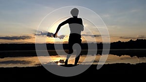 Jolly man dances rave on a lake bank at sunset in slo-mo