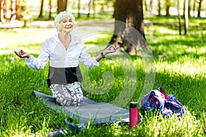 Jolly old lady making relaxation exercises in forest