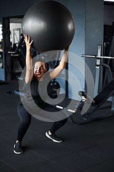 Jolly young woman doing buttocks workout with equipment