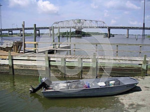 Jon boat with crab traps tied to dock and pushed up on boat land