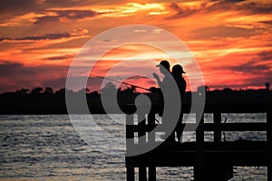 Jones Beach, New York - July 20, 2018 : Silhouettes of men fishing at the Jones Beach fishing piers right after a beautiful sunset