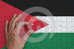 Jordan flag is depicted on a puzzle, which the man`s hand completes to fold