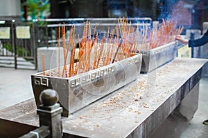 Joss sticks burning in sand tray in front of temple shrine, incense stick Asian traditional Chinese Buddhist temple
