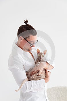 Joung man holding a cornish rex cat in his arms