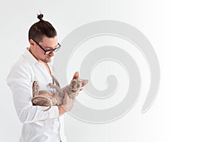 Joung man holding a cornish rex cat in his arms