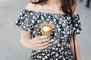 Joung woman holds vanilla ice cream in cone. .Vanilla ice cream in a waffle cone.