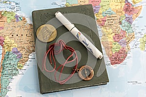 Journal with pen, talisman and coin on map