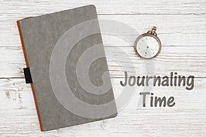 Journaling time with blank gray journal with pocket watch on a weathered whitewash wood background photo