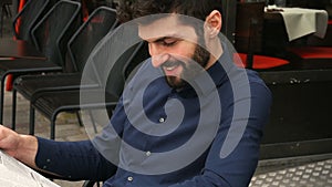 Journalist with close up face reading newspaper article at cafe table in slow motion.