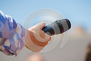 The journalist holds a microphone in his hand during an interview_