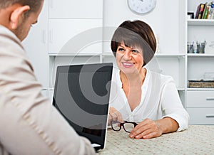 Journalist with laptop interviews the elderly wealthy woman