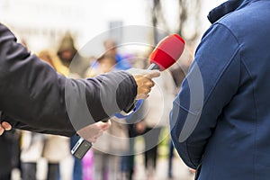 Journalist making media or vox pop interview with unrecognizable man on the street