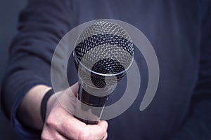 Journalist making speech with microphone and hand.