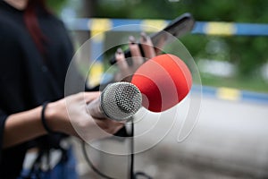 Journalist at news conference, recording notes, holding microphones and smartphone dictaphone