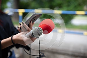 Journalist at news conference, recording notes, holding microphones and smartphone dictaphone