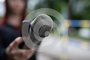 Journalist at news conference, recording notes, holding microphones and smartphone dictaphone