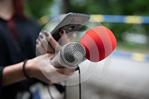 Journalist at news conference, recording notes, holding microphones and smartphone dictaphone