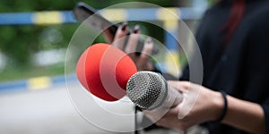 Journalist at news conference, recording notes, holding microphones and smartphone dictaphone