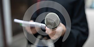 Journalist at news conference, writing notes, holding microphones