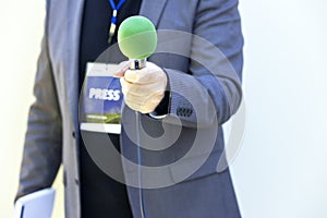 Journalist at news event, press conference or media interview holding green microphone. Broadcast journalism concept.