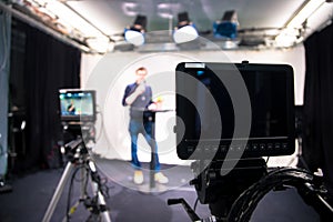 Journalist in a television studio is talking into a microphone, blurry film cameras