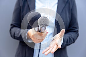 Journalist or TV reporter holding microphone and making media interview. Broadcast journalism concept.