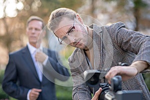 Fair-haired male journalist fitting camera to tripod, getting ready for interview