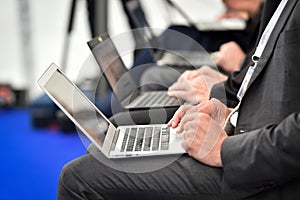 Journalists hands typing on laptops during a press conference