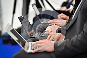 Journalists hands typing on laptops during a press conference