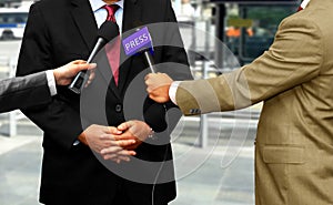 Journalists with microphones interviewing corporate spokesperson