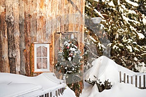 A journey into a fairy tale. A wooden fairy-tale house with a Christmas wreath on the door in the snow