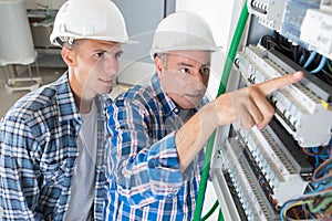 Journeyman and apprentice electrician working to repair circuit panel