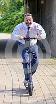 Jovial businessman yelling as he speeds along on a scooter