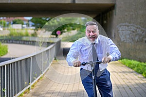 Jovial businessman yelling as he speeds along on a scooter photo